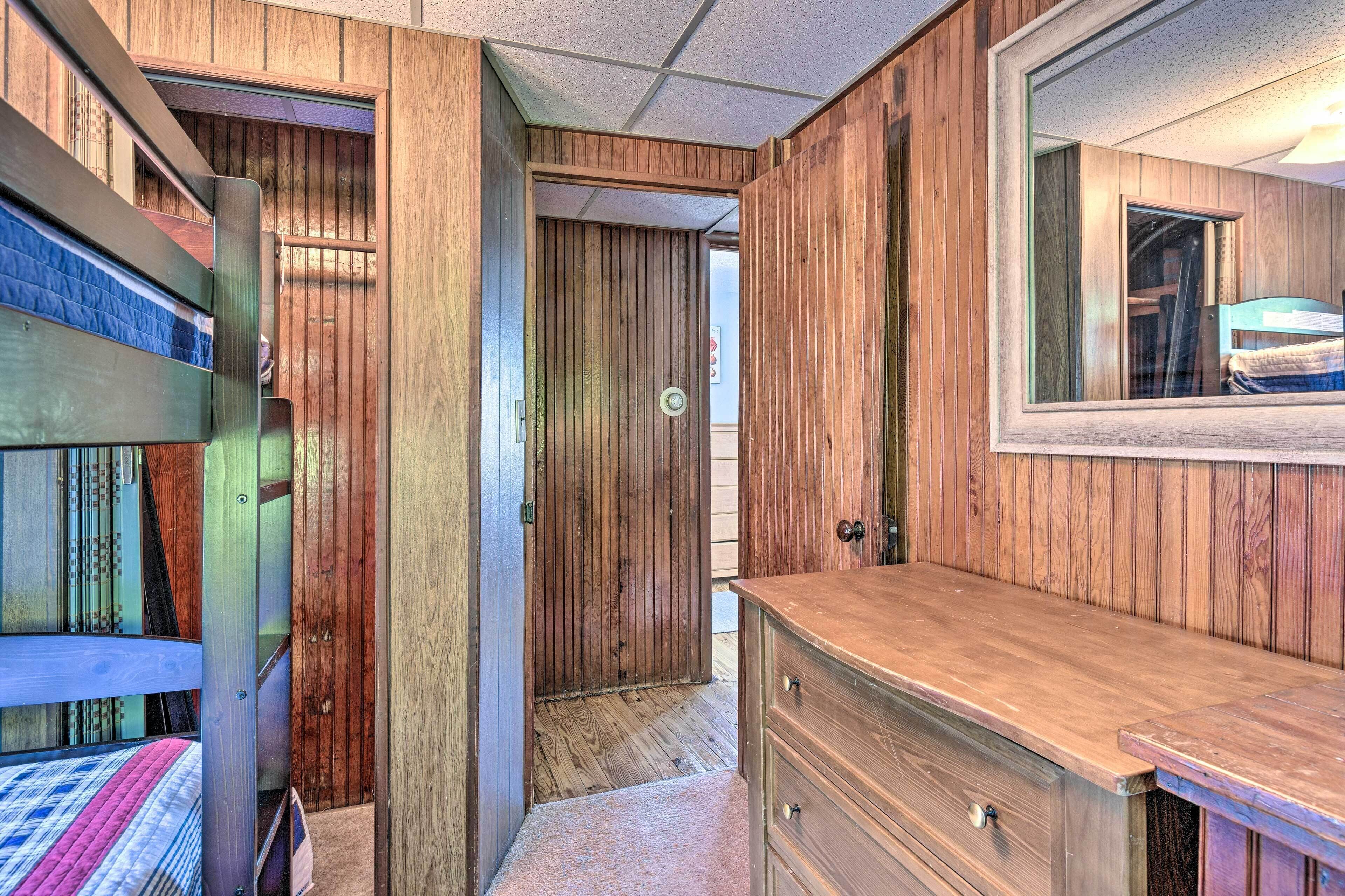 Un interior de madera con literas, un aparador de madera y una puerta que da a otra habitación.