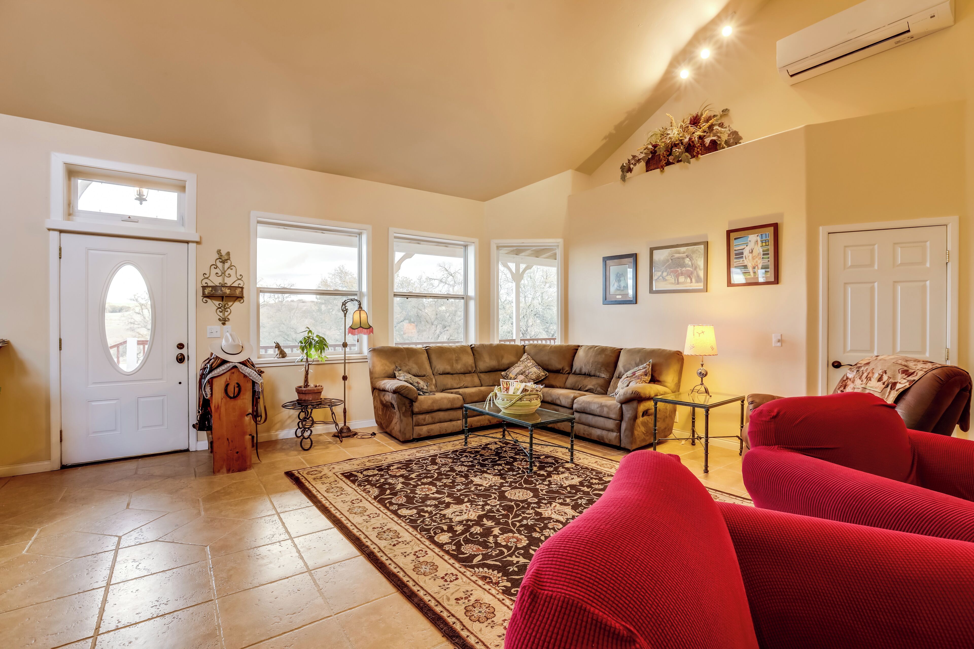 A living room with a sofa, red armchairs, a coffee table, and a patterned rug.