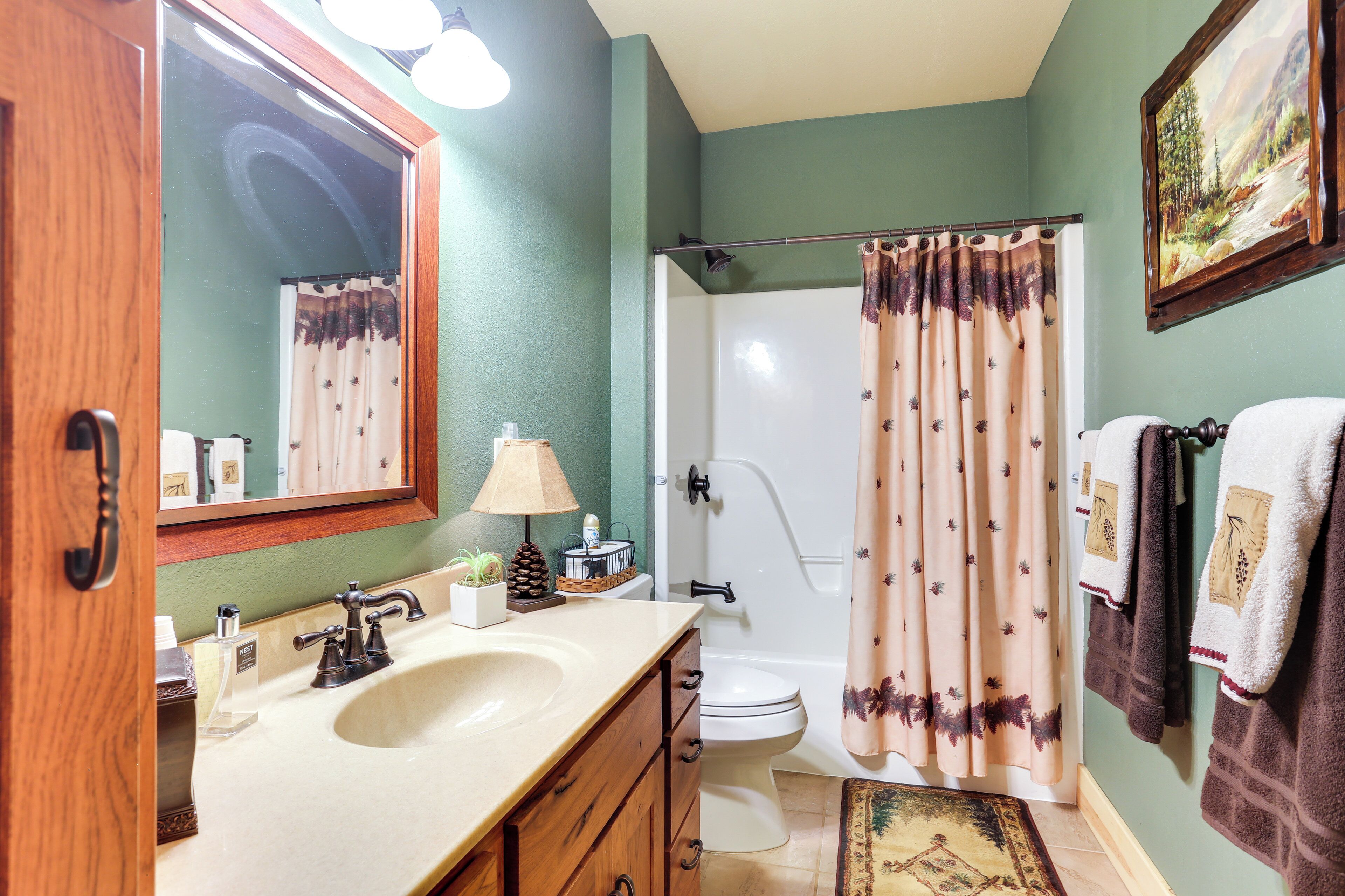Une salle de bain avec un meuble-lavabo en bois, un évier, des toilettes et une douche avec un rideau.