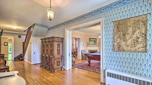 A spacious room with hardwood floors, a large wooden cabinet, a billiards table, and a fireplace. - Lush Elkin Home w/ Porch Views & Pool Table (Elkin)