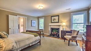 A bedroom with a bed, a chair, a fireplace, and a dresser. - Lush Elkin Home w/ Porch Views & Pool Table (Elkin)