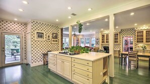 A spacious kitchen with a central island, wooden cabinets, and a dining area with chairs. - Lush Elkin Home w/ Porch Views & Pool Table (Elkin)