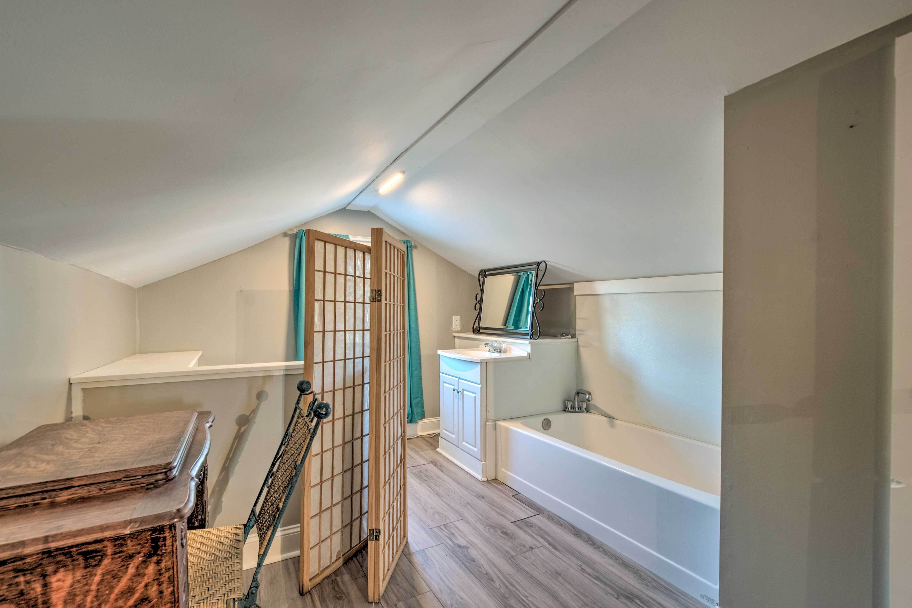 Une chambre à coucher de taille modeste, avec un plafond en pente, une armoire en bois, une petite table et un lit simple.