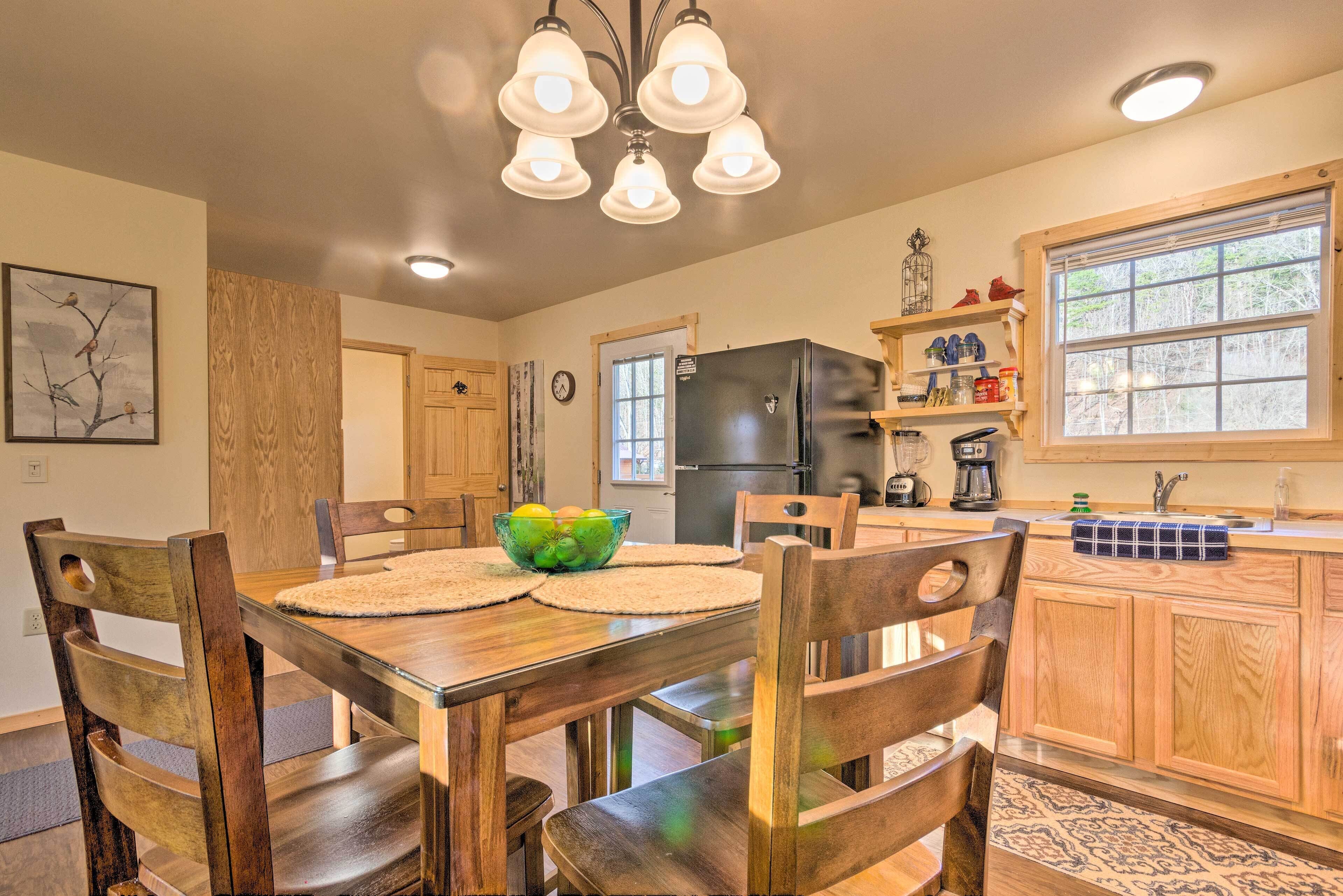 Una cocina con armarios de madera, un refrigerador negro y una mesa de comedor con sillas.
