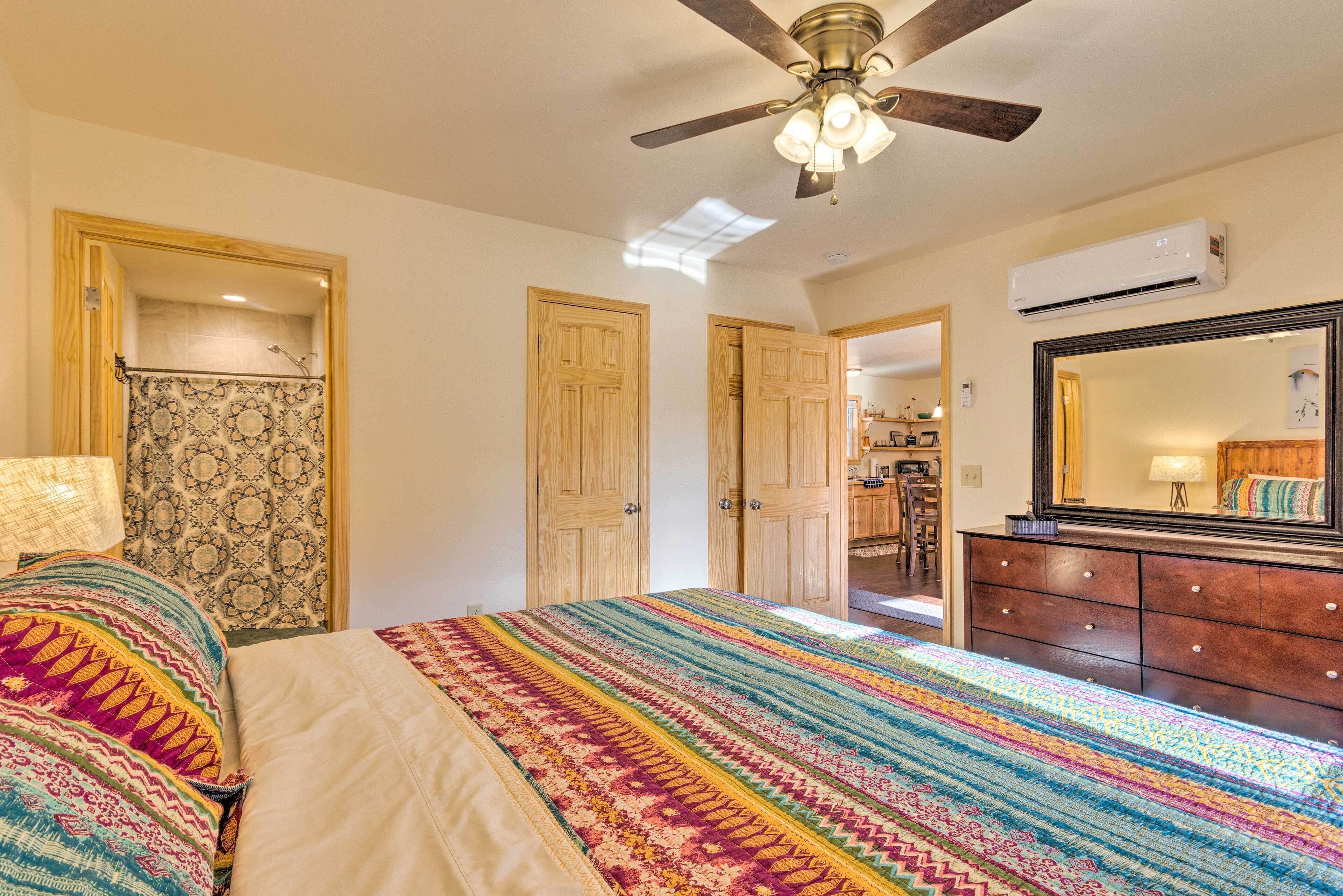 A bedroom with a bed, a ceiling fan, a dresser, and a mirror.