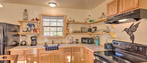 A kitchen with wooden cabinets, a stove, a microwave, and a window.