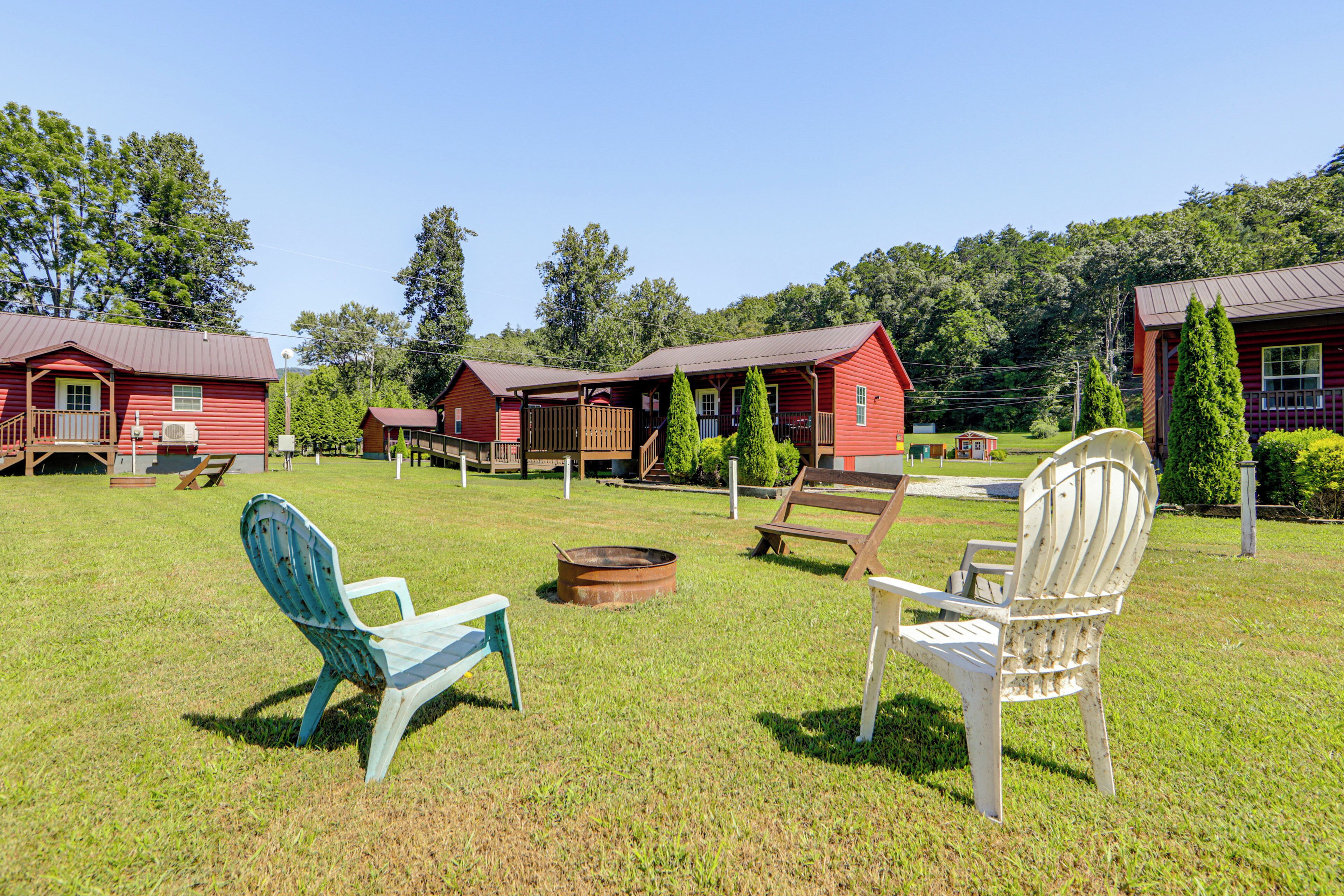 A rustic cabin-style hotel with multiple red buildings, outdoor seating, and a well-maintained lawn.