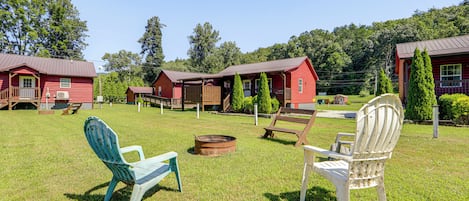 A rustic cabin-style hotel with multiple red buildings, outdoor seating, and a well-maintained lawn.