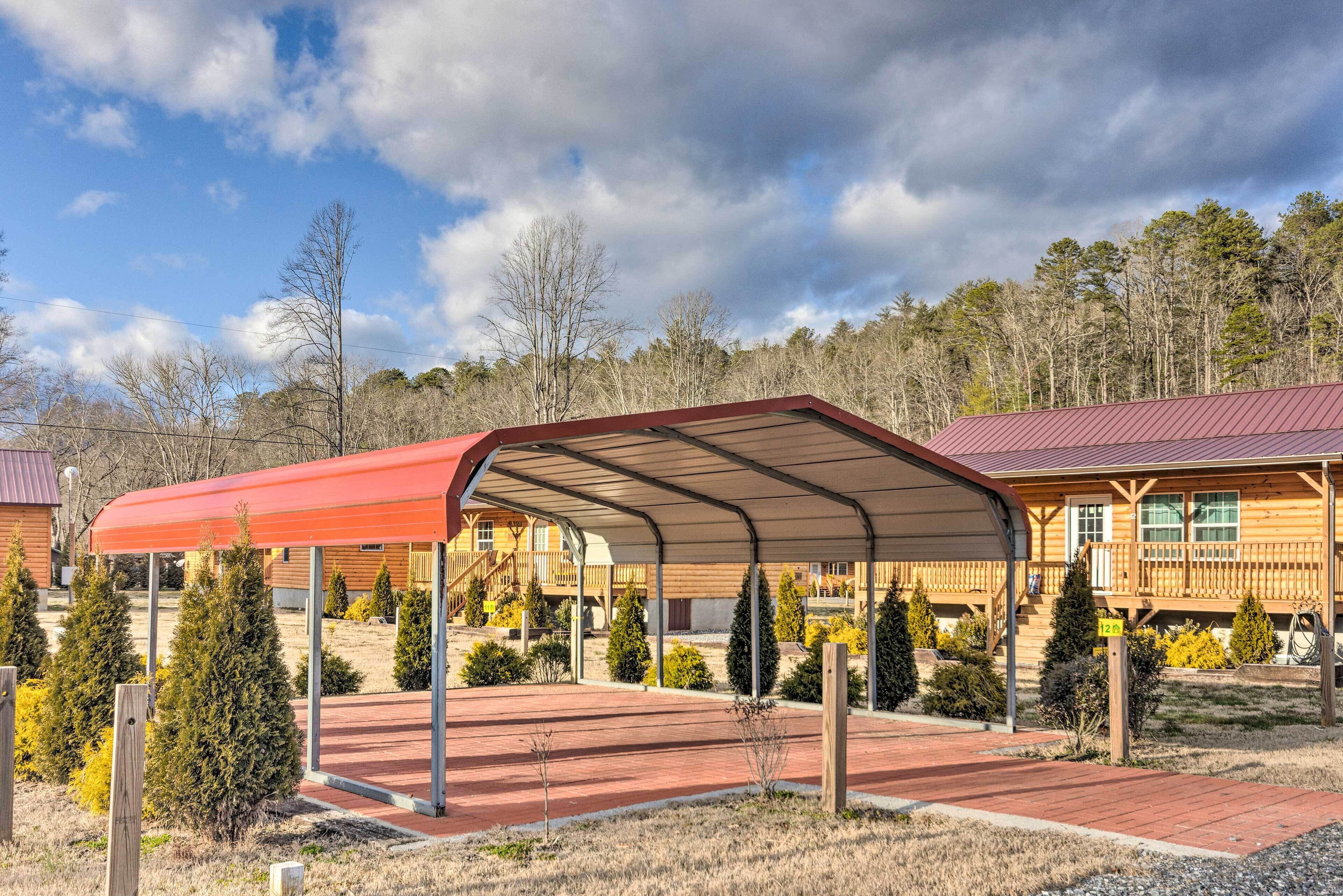 Un espace extérieur abrité, doté d’un toit rouge, de cabanes en bois et surplombant une zone boisée.