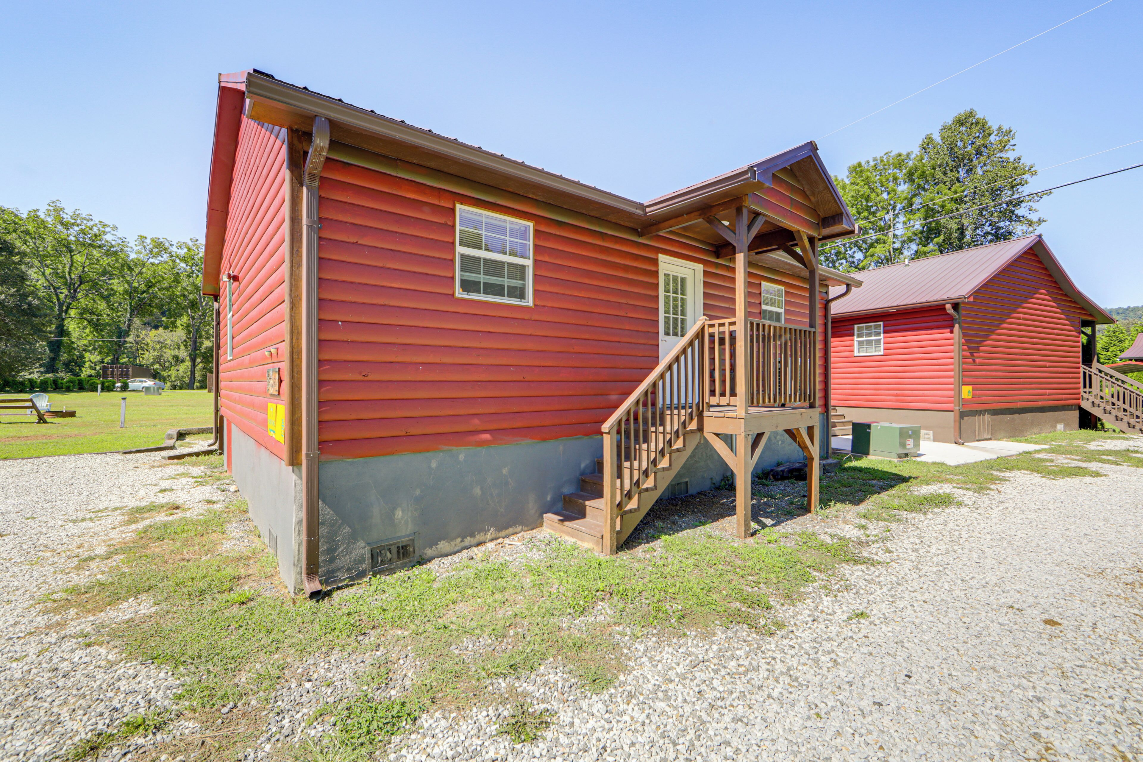 A red wooden building with a porch and wooden steps leading to a door.