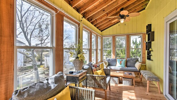A sunlit room with large windows, wooden ceiling beams, and a variety of seating including a sofa and chairs. - High-end Canal Front Paradise in Kill Devil Hills (Kill Devil Hills)