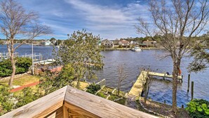 A waterfront property with a dock, boats, and houses in the background. - High-end Canal Front Paradise in Kill Devil Hills (Kill Devil Hills)