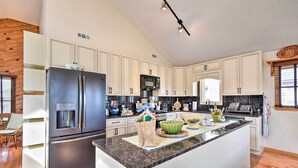 A modern kitchen with white cabinets, stainless steel appliances, and a granite countertop. - High-end Canal Front Paradise in Kill Devil Hills (Kill Devil Hills)