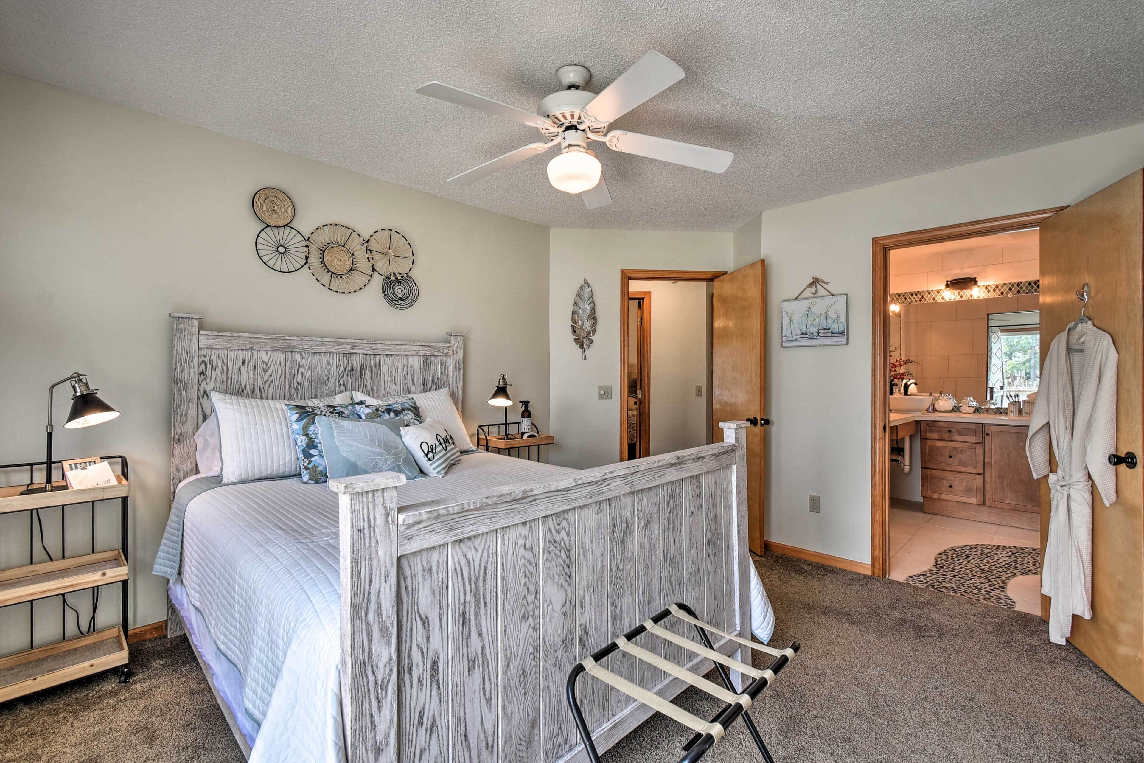A bedroom with a wooden headboard, a ceiling fan, a bedside table with a lamp, and a wardrobe.