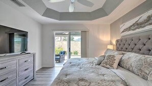 Quarto com cama, cômoda, ventilador de teto e vista para o exterior.