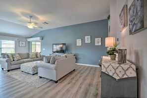 A modern living room with a grey sofa set, a TV, and a decorative table with a lamp.