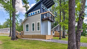 Une cabane moderne dotée d’une terrasse, entourée d’arbres.