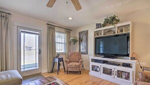 A living room with a television, a patterned armchair, a coffee table with books, and a white entertainment unit with shelves. - Jersey Shore Getaway w/ Grill: Walk to Beach! (Belmar)