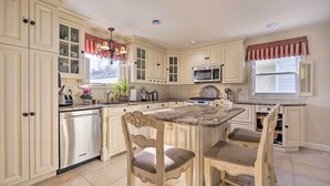 A kitchen with white cabinetry, a central island with bar stools, a microwave, and a chandelier. - Jersey Shore Getaway w/ Grill: Walk to Beach! (Belmar)