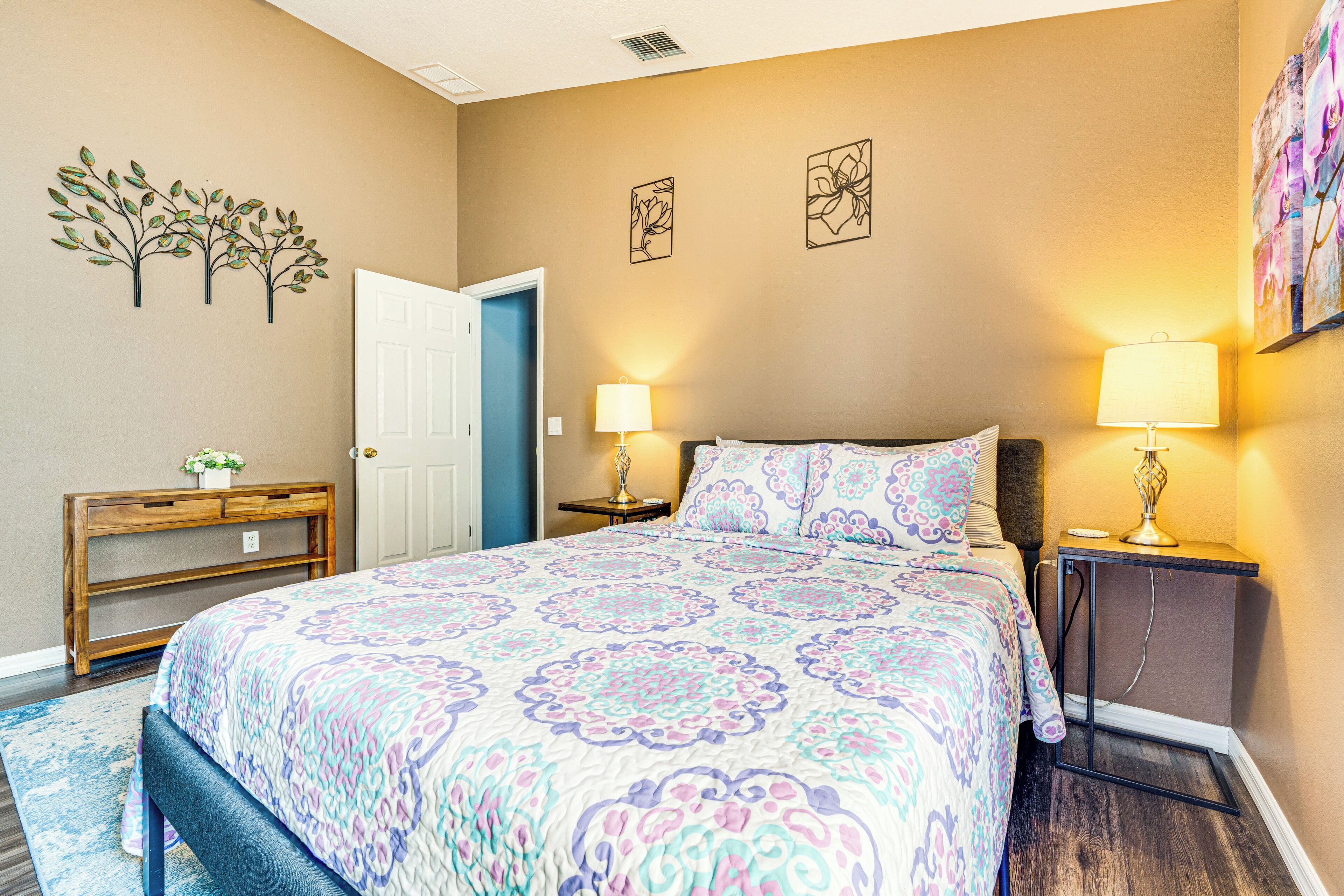A bedroom with a large bed, bedside lamps, a wooden nightstand, and a door.