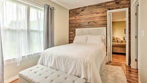 Een slaapkamer met een bed, een plafondventilator en uitzicht op een andere kamer.