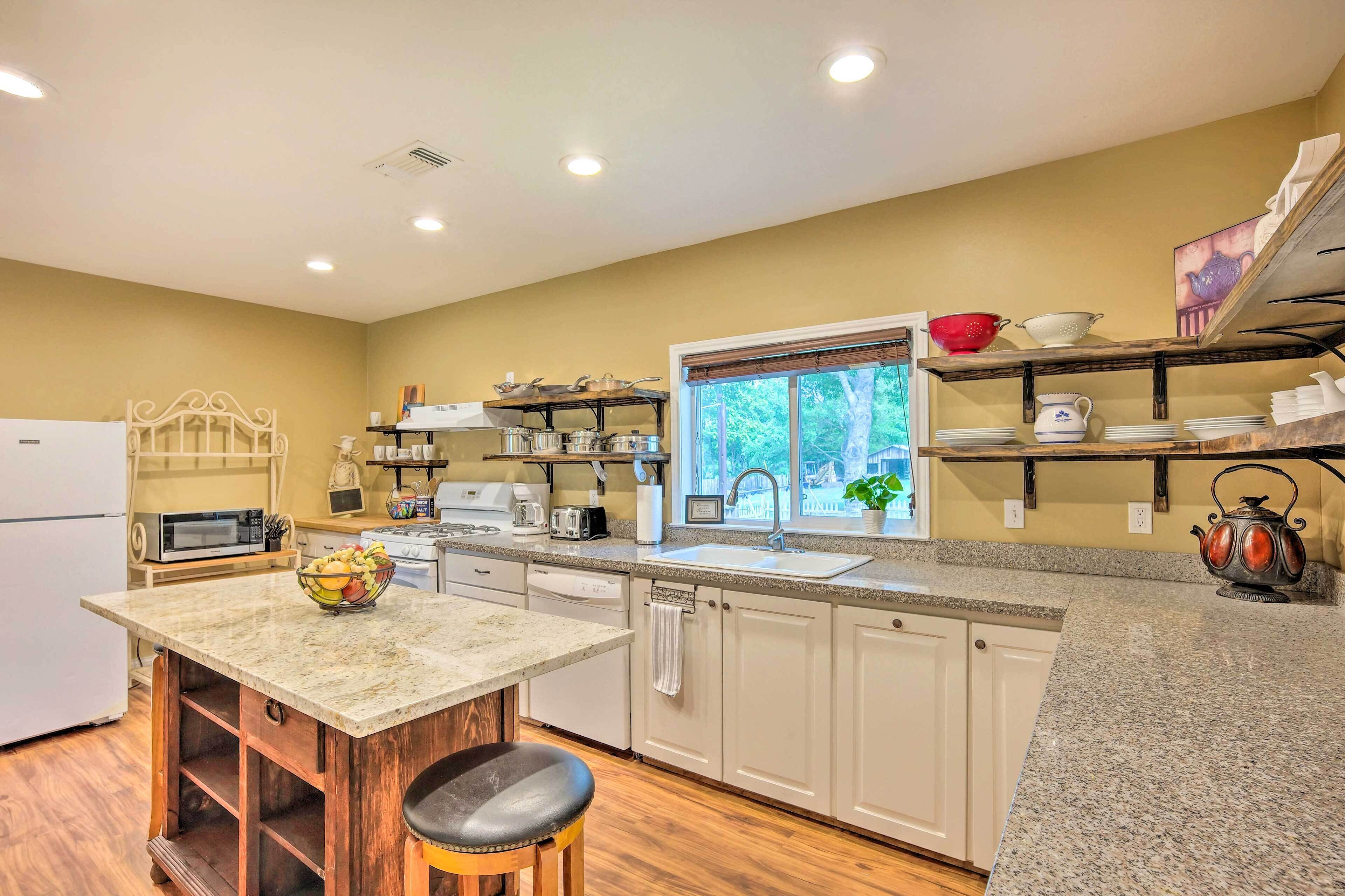 A kitchen with a granite countertop, white cabinets, a window with a view, and a sink.