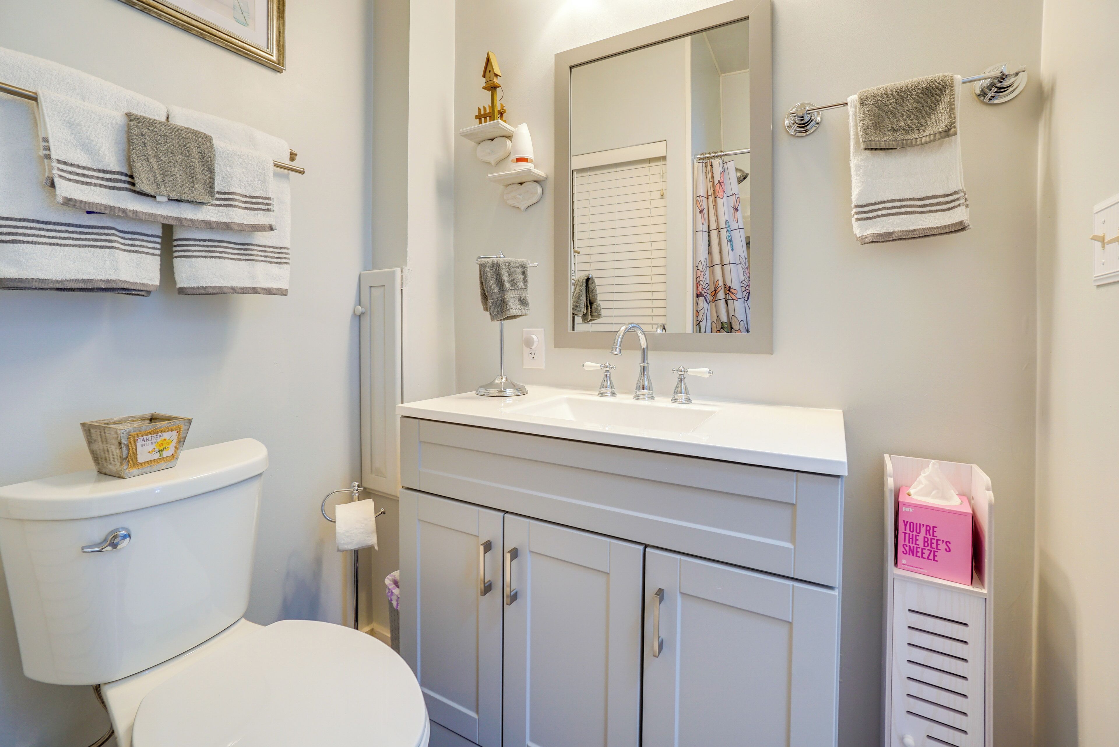 A bathroom with a toilet, sink, vanity, and towel rack.
