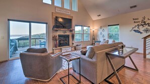 A spacious living room with a fireplace, large windows, and a view of the outdoors.