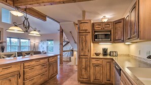 A spacious kitchen with wooden cabinetry, a large island, and a microwave.