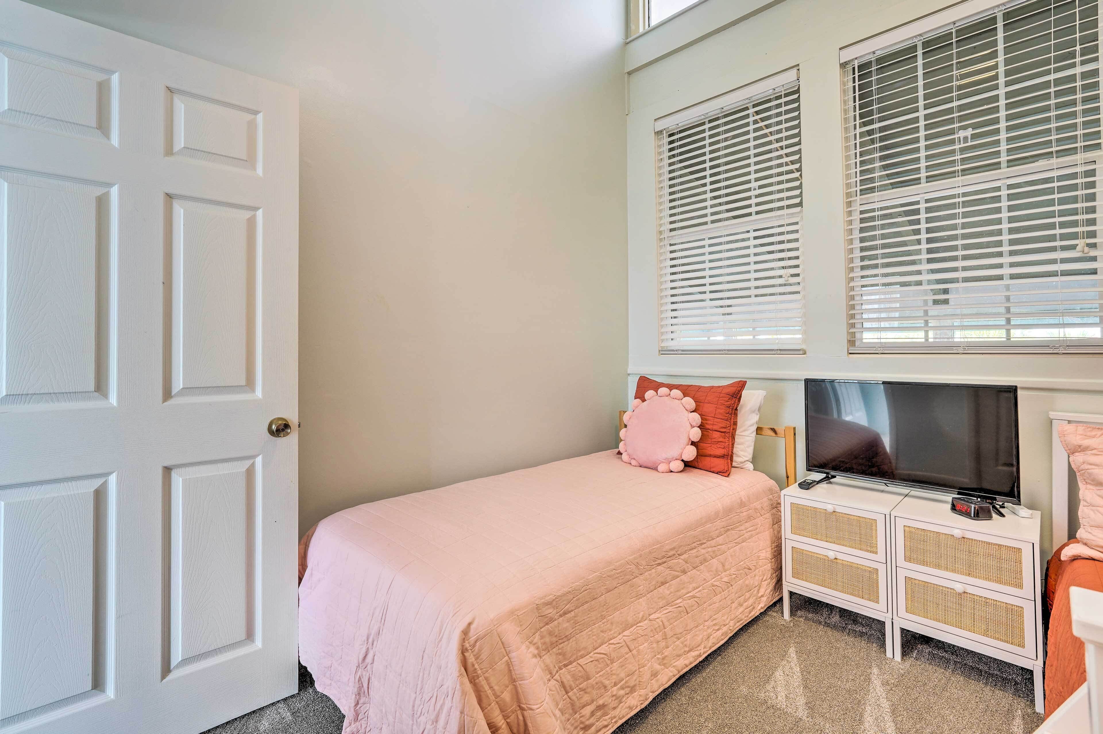 A bedroom with a single bed, a TV, and a dresser.