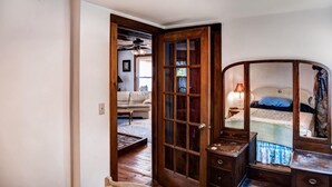 Ein Zimmer mit einer Holztür, die in einen Wohnbereich mit einer Couch und einer Lampe führt.