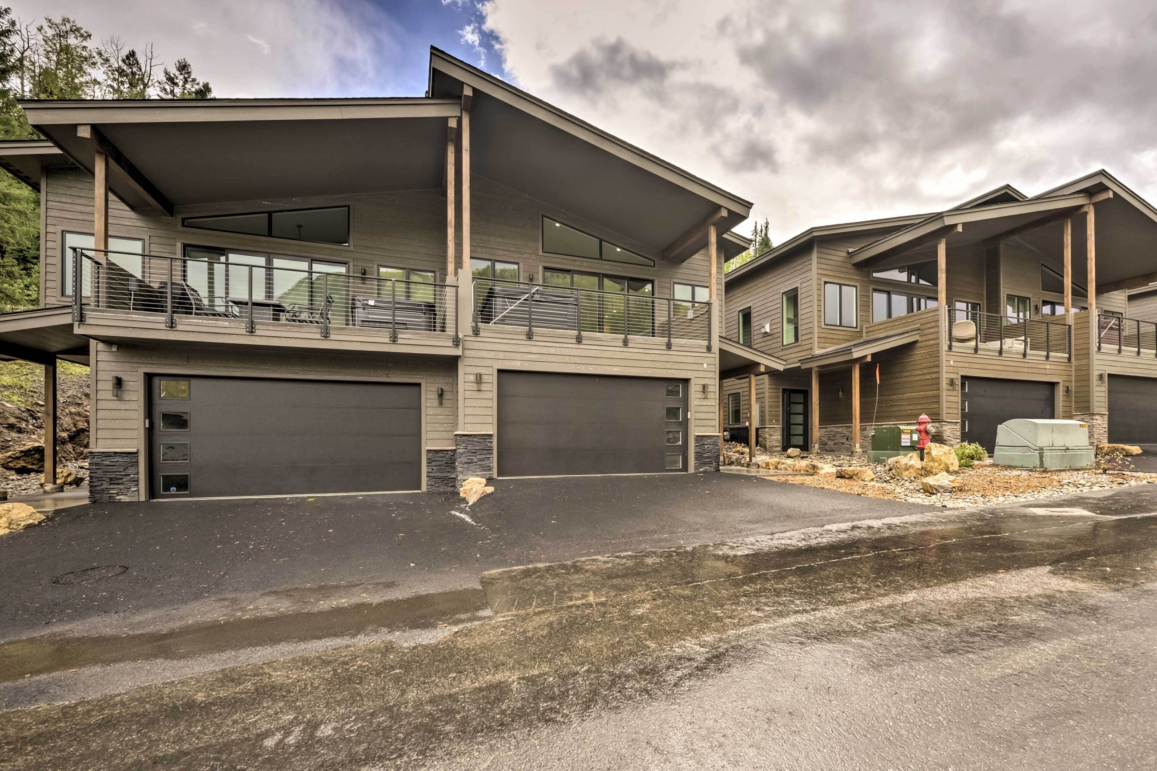A modern multi-story residential building with a garage, balconies, and a covered driveway.