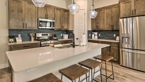 A modern kitchen with wooden cabinets, stainless steel appliances, and a central island with bar stools.