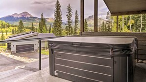 A room with a large window overlooking a mountainous landscape, a wooden deck, and a black storage unit.