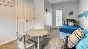 A room with a dining table and chairs, a blue sofa with patterned cushions, and a door with a sign above it. - Beach & Pool Access at Lake Travis Family Getaway! (Leander)