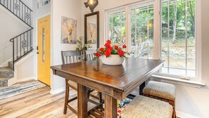 A dining area with a wooden table, chairs, and a vase of red flowers. - Beach & Pool Access at Lake Travis Family Getaway! (Leander)