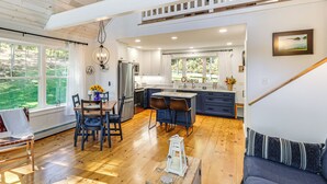 A spacious kitchen with a dining area, wooden floors, and large windows. - Sunny Stockton Springs Home < 1 Mi to Beach! (Stockton Springs)