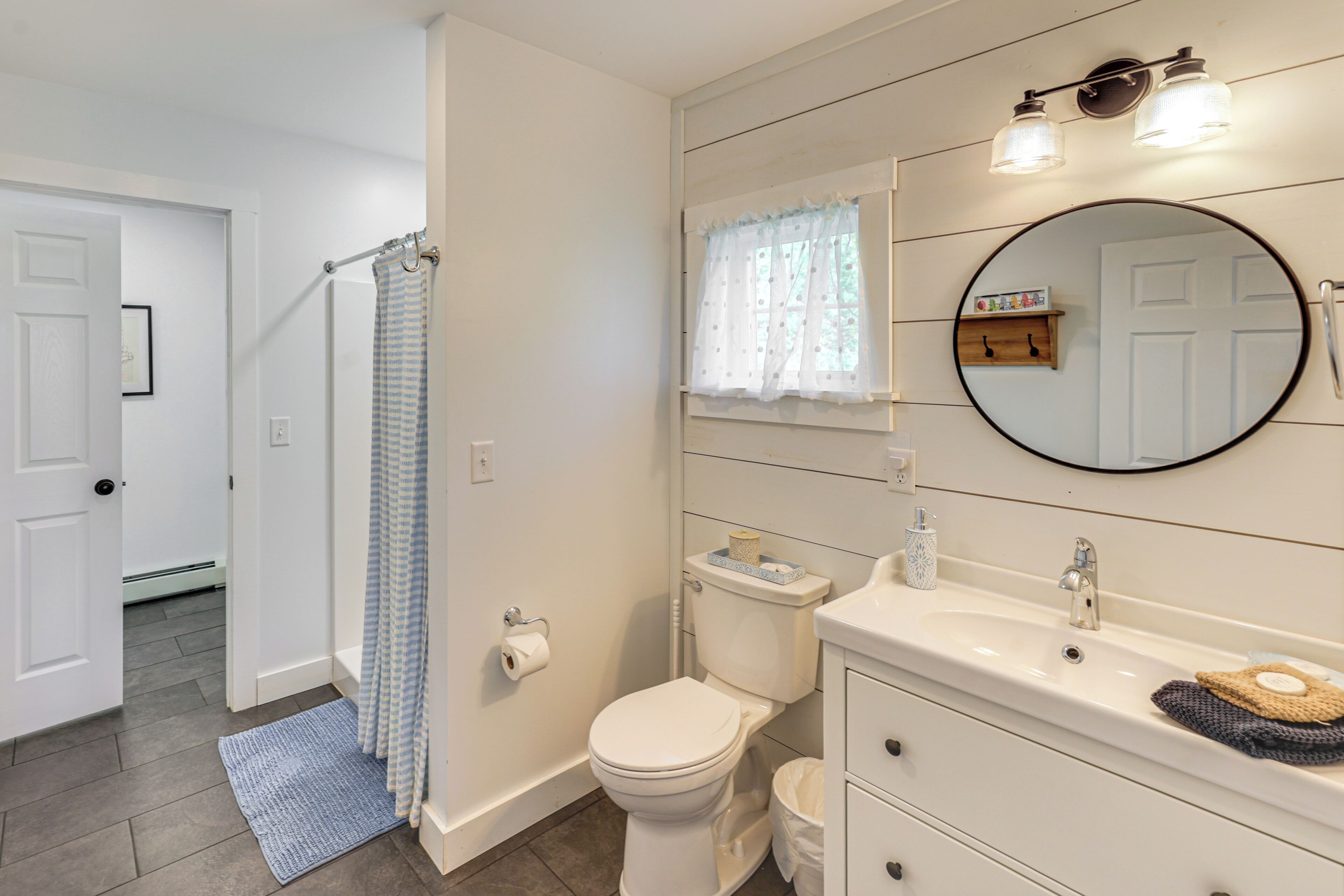 A bathroom with a toilet, sink, mirror, and shower curtain.