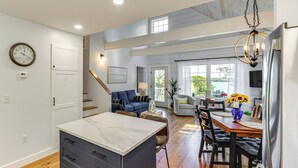 A spacious kitchen with a marble countertop, wooden flooring, and a dining area with a table and chairs. - Sunny Stockton Springs Home < 1 Mi to Beach! (Stockton Springs)