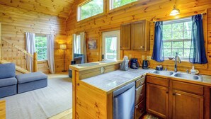 L’intérieur d’un chalet en bois comprend une cuisine, un coin repas et un escalier.