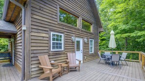 Une cabane en bois dotée d’une terrasse, de meubles d’extérieur et d’une porte.