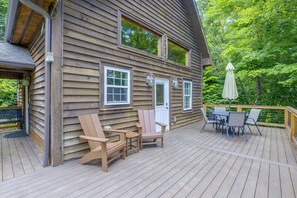 Una cabaña de madera con terraza, asientos exteriores y una puerta.