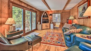 A cozy living room with a leather sofa, a patterned rug, and wooden walls. - Waterfront Whitefish Lake Home w/ Dock! (Pine River)