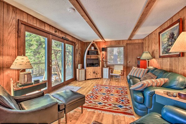 A cozy room with a wooden interior, a leather sofa, a television, and a large window.
