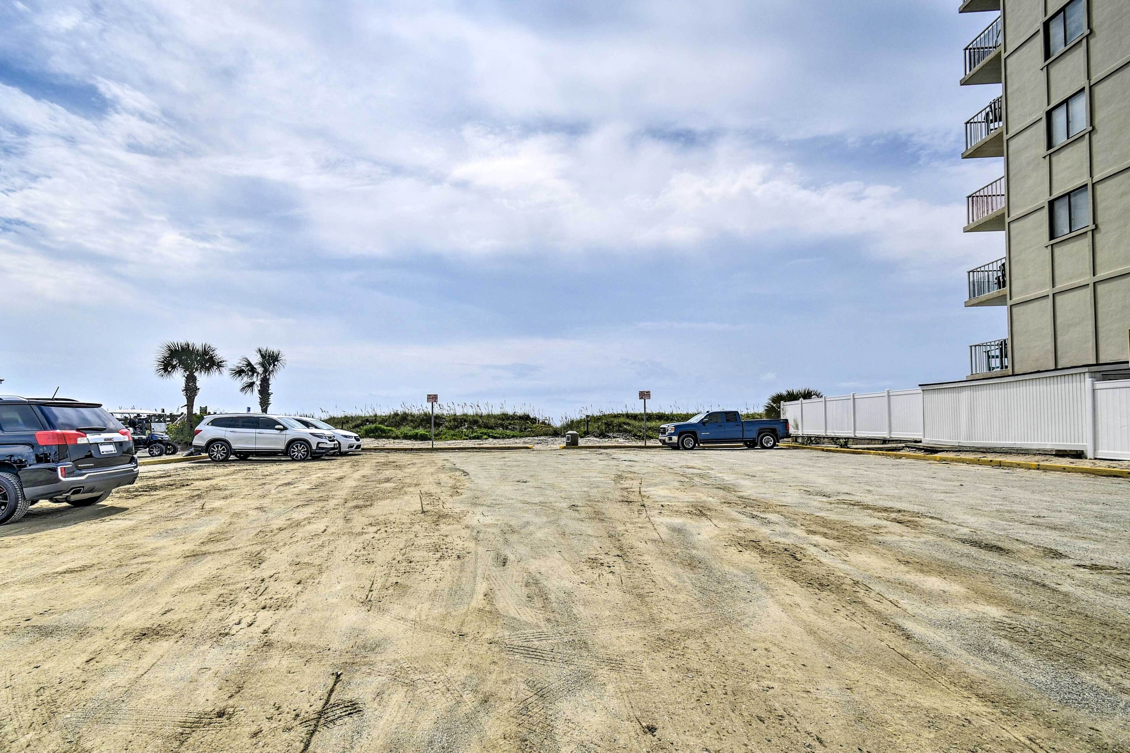 Ein Parkplatz mit mehreren Autos, ein Gebäude mit Balkonen und einem klaren Himmel.
