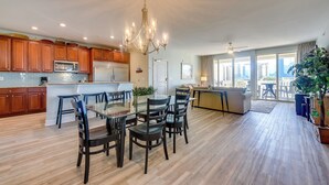 A spacious kitchen with wooden cabinets, a central island, and a dining area with chairs. - Walk to Shore: Roomy Condo in North Myrtle Beach! (North Myrtle Beach)