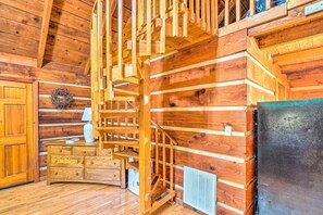 Un intérieur en bois avec un escalier en colimaçon, une cheminée et une commode en bois.