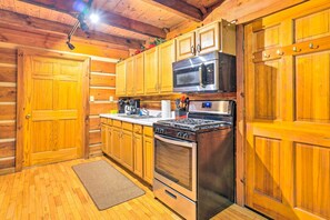Una cucina in stile baita in legno, con fornello, forno, microonde e pensili in legno.