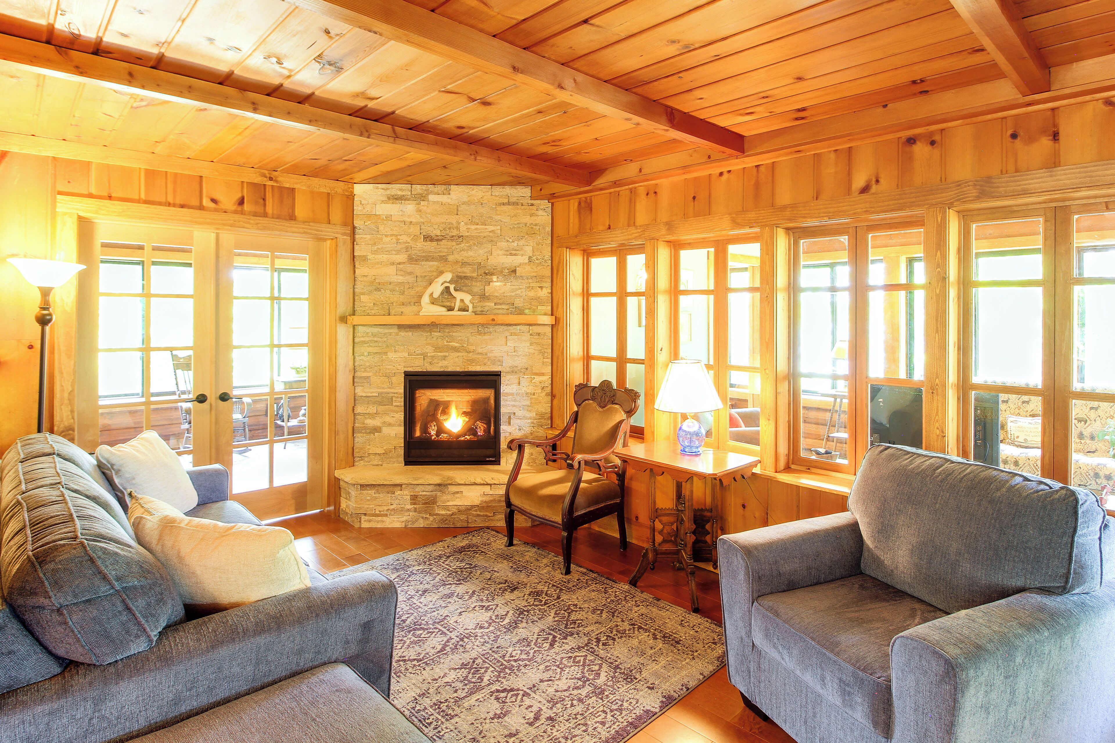 Un salón acogedor con chimenea, paredes de madera y asientos cómodos.