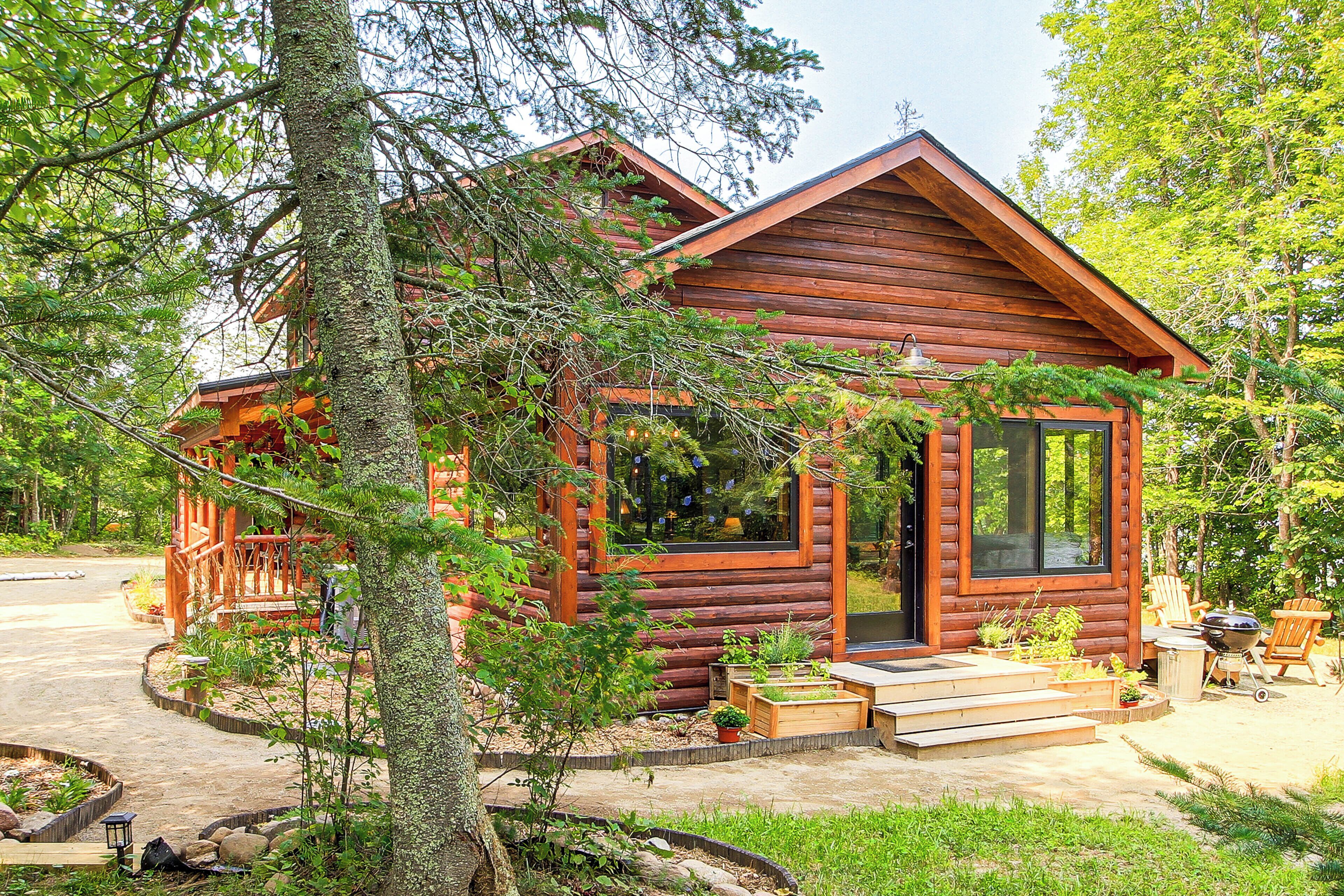 A wooden cabin with a porch, a large window, and a door.